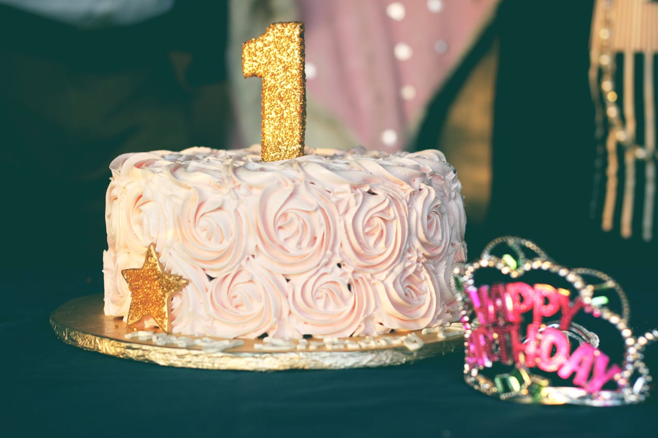 A beautiful first birthday cake adorned with pink rosette frosting and golden decorations. Perfect for celebrations.